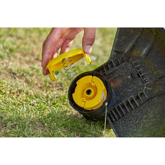 STANLEY SFMCST933M1 grastrimmer spoelmontage op gazon, gele kap en veer detail.