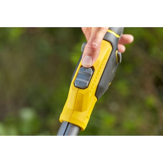 Foto van STANLEY SFMCSTB933M grastrimmer handgreep close-up met gele grip en dubbele snelheidsregelaar.