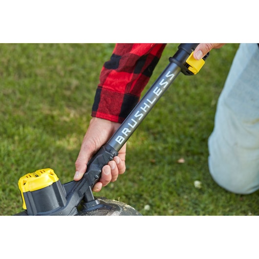 Stanley SFMCSTB933M brushless grastrimmer met gele batterij, close-up op gras.
