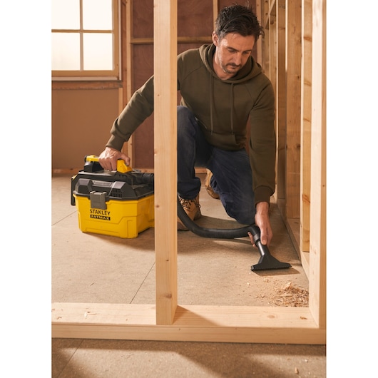 Photo de l’aspirateur eau et poussière STANLEY SFMCV002B, jaune et noir, utilisé pour nettoyer des débris de chantier.