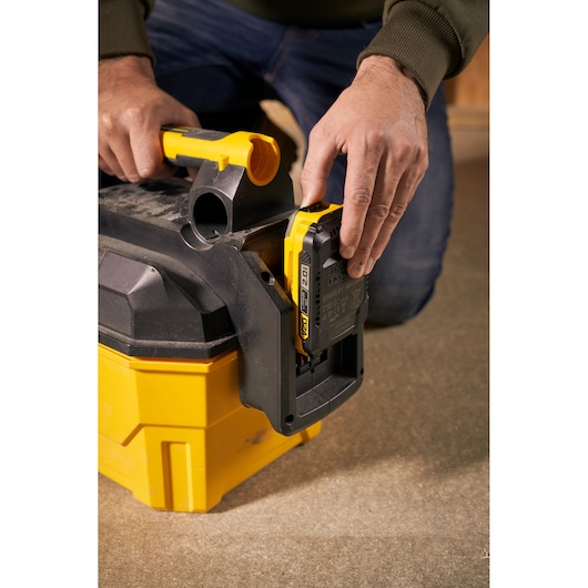 STANLEY SFMCV002B aspirateur portatif gros plan du compartiment batterie avec une personne insérant la batterie.