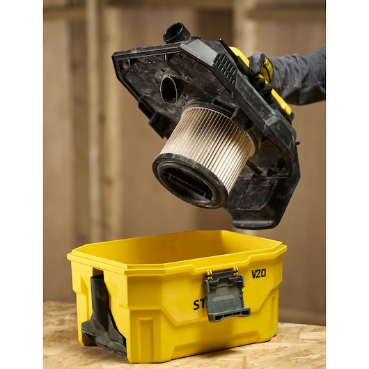 STANLEY V20 stofzuigerfilter en deksel worden van een gele behuizing in een werkplaats getild.