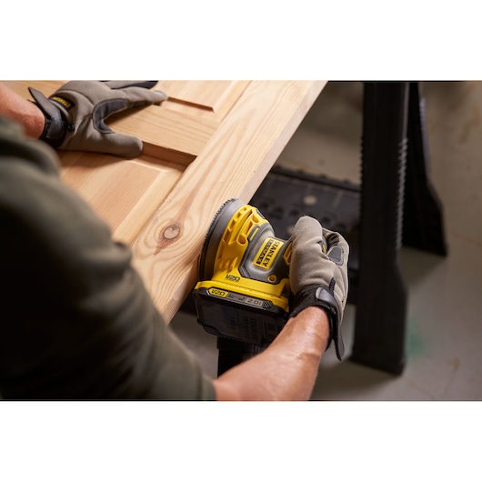 Photo de la ponceuse sans fil STANLEY SFMCW220B utilisée sur une surface en bois, vue rapprochée.