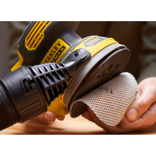 STANLEY SFMCW220D1S schuurmachine close-up met schuurschijf vastgehouden door hand