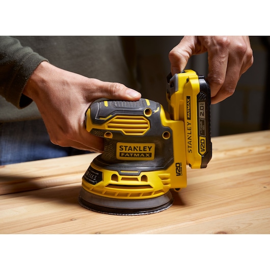 STANLEY SFMCW220D1S draadloze schuurmachine, geel en zwart, close-up op houten oppervlak.