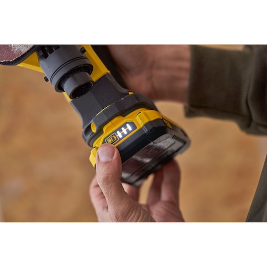 STANLEY SFMCW221D1S geel snoerloos gereedschap close-up met batterij-indicator, hand drukt knop.
