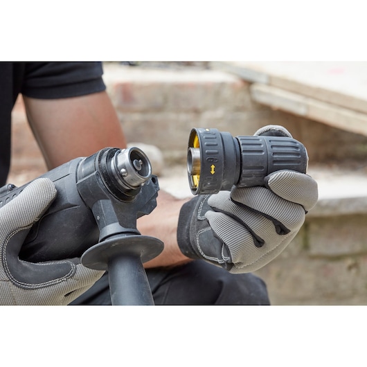 STANLEY SFMEH210K-QS rotatiehamer met accessoire, vastgehouden door handschoenen, buiten close-up.