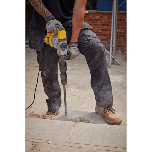 Stanley SFMEH220K-QS breekhamer in gebruik, beton buiten brekend, close-up van gereedschap en handen.