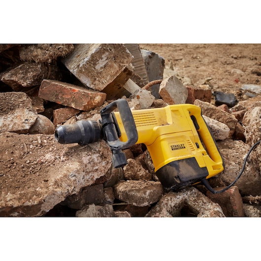 STANLEY SFMEH230K-QS sloophamer op puin, gele behuizing met zwarte handgreep, zijaanzicht.