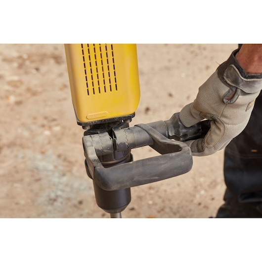 Foto van STANLEY SFMEH230K-QS hamerboor handgreep vastgehouden door een handschoenhand, buiten close-up.