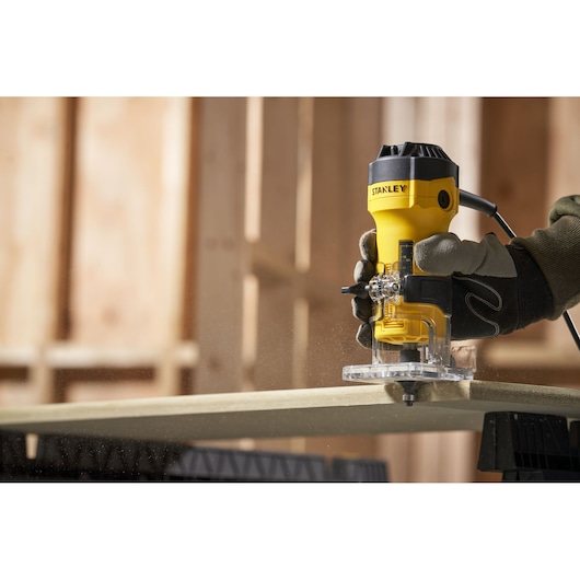 STANLEY ST55 défonceuse compacte utilisée sur du bois avec une main gantée, atelier intérieur.