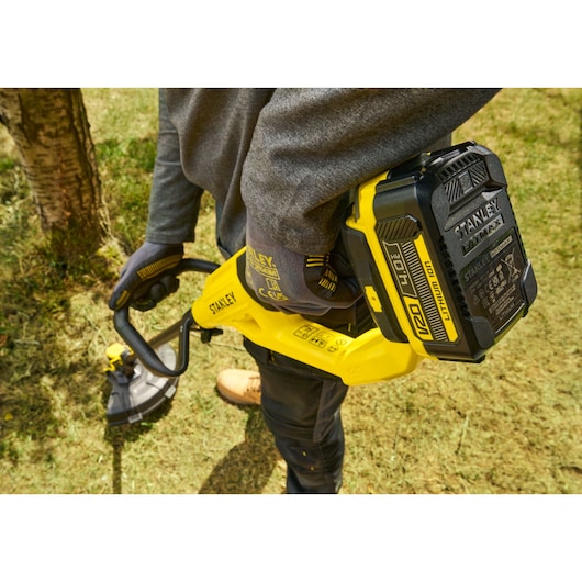 STANLEY STCST933B coupe-herbe sans fil utilisé en extérieur, gros plan, design jaune et noir.