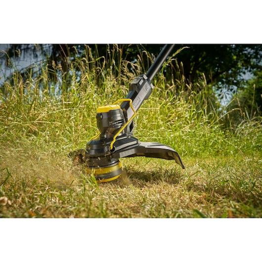 STANLEY STCST933M1 coupe-bordures coupant l'herbe haute, gros plan en extérieur.