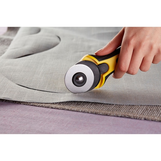 Outil cutter rotatif STANLEY STHT0-10194 coupant un tissu gris en gros plan.