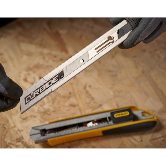 STANLEY STHT0-11825 couteau utilitaire avec lame sortie, manche jaune et noir, gros plan sur surface en bois.