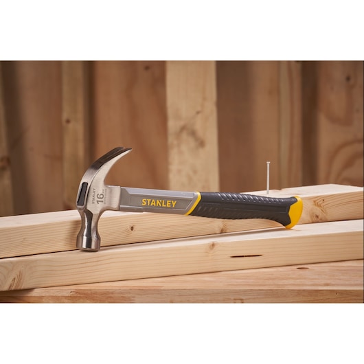 STANLEY STHT0-51309 klauwhamer met zwart en geel handvat op houten planken, zijaanzicht.