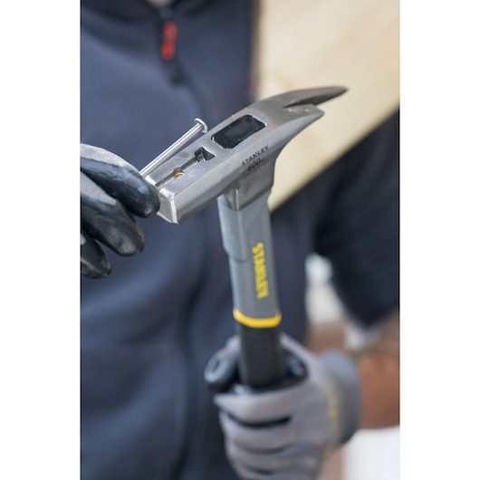 Marteau STANLEY STHT0-51311 tenu avec des gants, démontrant la fonction de démarreur de clous.
