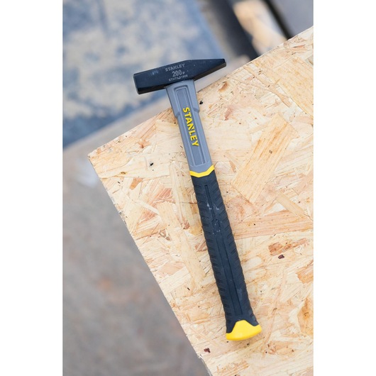 STANLEY STHT0-51906 hamer met zwart-geel handvat, zijaanzicht, op houten plaat.
