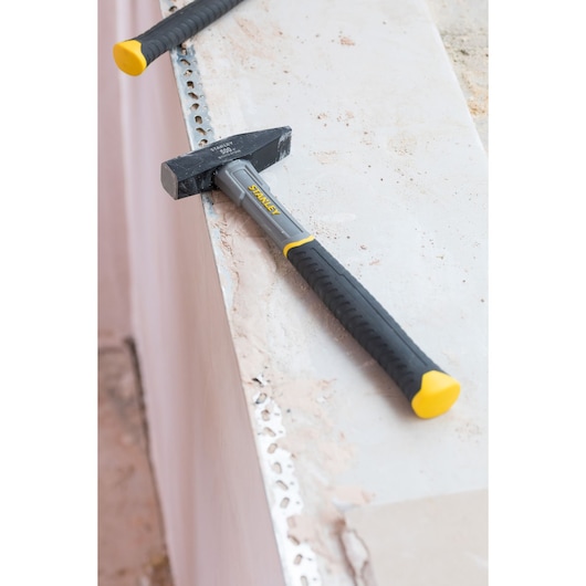 STANLEY STHT0-51908 stalen hamer met zwart-gele handgreep op betonoppervlak, productfotografie.
