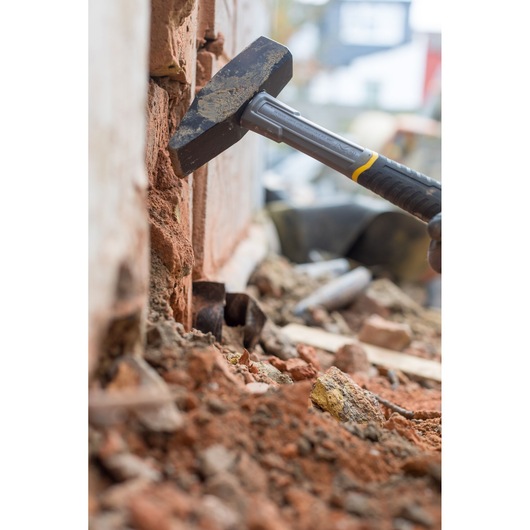 Marteau STANLEY STHT0-51910 cassant un mur en briques, gros plan sur chantier.