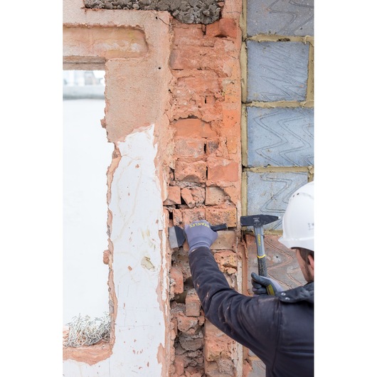 STANLEY STHT0-51910 marteau à briques utilisé sur chantier, ouvrier détruisant un mur de briques.