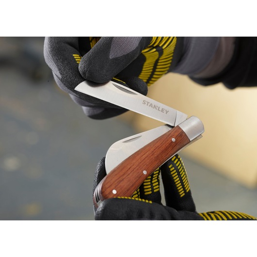 STANLEY STHT0-62687 vouwzakmes met houten handvat, close-up vastgehouden door handschoenen.
