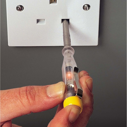 Testeur de tension STANLEY STHT0-66121 utilisé sur une prise électrique, vue rapprochée.