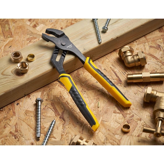 STANLEY STHT0-74361 pince réglable à poignées jaune et noire sur bois avec raccords et vis de plomberie.