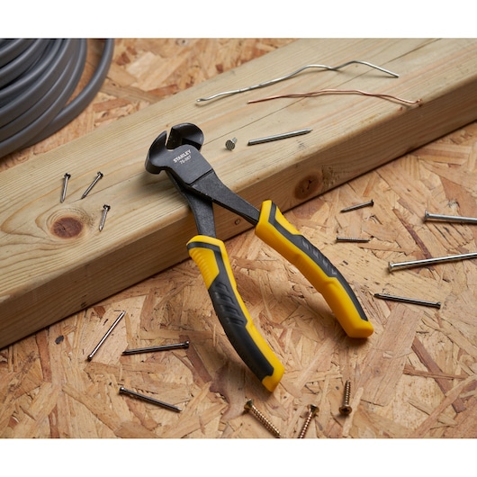 STANLEY STHT0-75067 pince coupante à poignées jaunes et noires sur bois, entourée de clous et fils.
