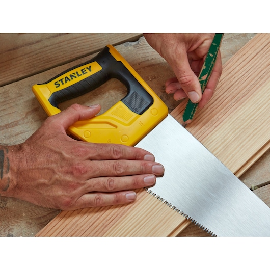 Foto van STANLEY STHT1-20353 handzaag met geel-zwarte handgreep die een houten plank zaagt.