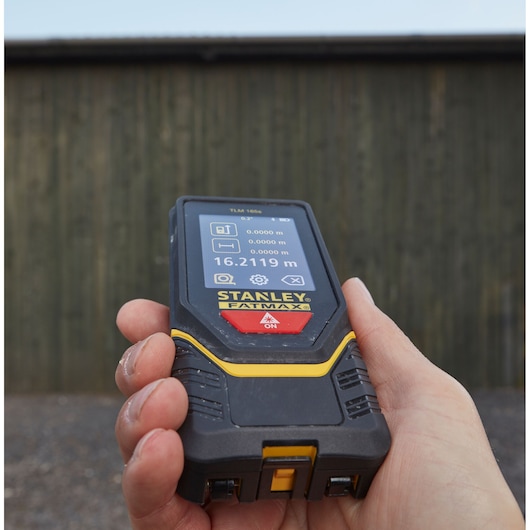 Foto van een STANLEY STHT1-77139 laserafstandsmeter in de hand, scherm toont meting in meters.