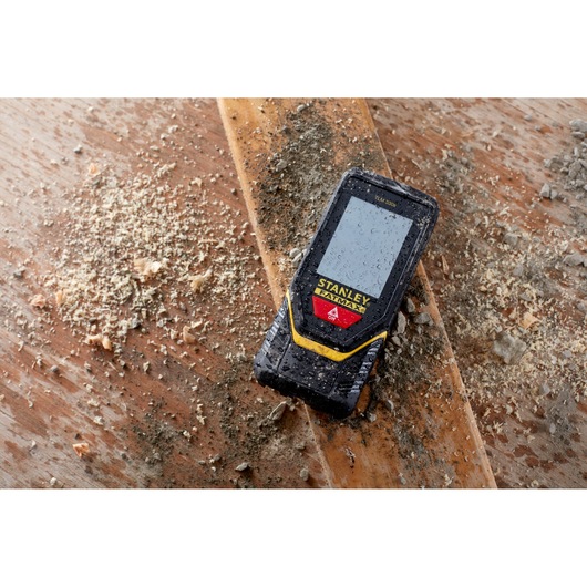 STANLEY STHT1-77140 télémètre laser sur surface en bois poussiéreuse, conception robuste et résistante à l'eau.
