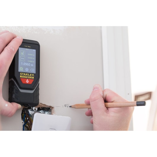 Stanley STHT1-77142 télémètre laser en utilisation, main inscrivant la mesure sur le mur.