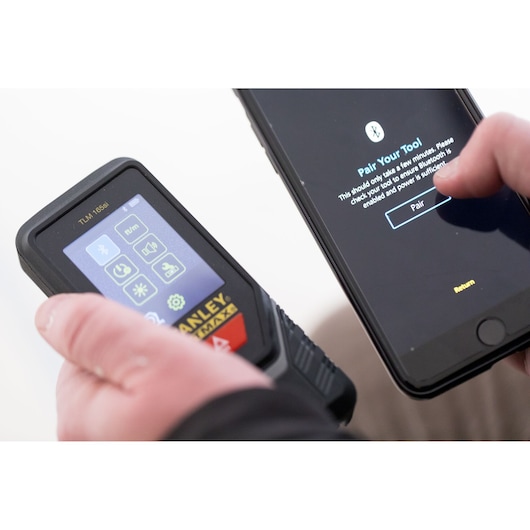 Télémètre laser STANLEY STHT1-77142 couplé à un smartphone via Bluetooth, vue rapprochée.