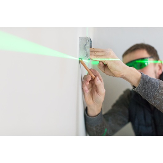 STANLEY STHT1-77367 laserwaterpas projecteert groene lijn op de muur, gebruikt voor positionering tijdens installatie.