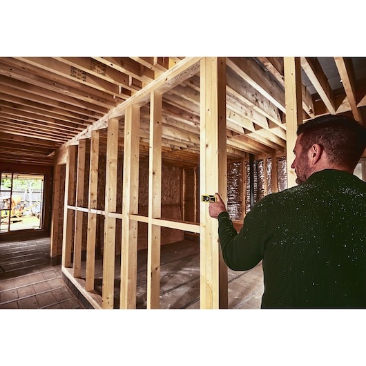 STANLEY STHT1-77409 télémètre laser utilisé sur un chantier de construction en bois.