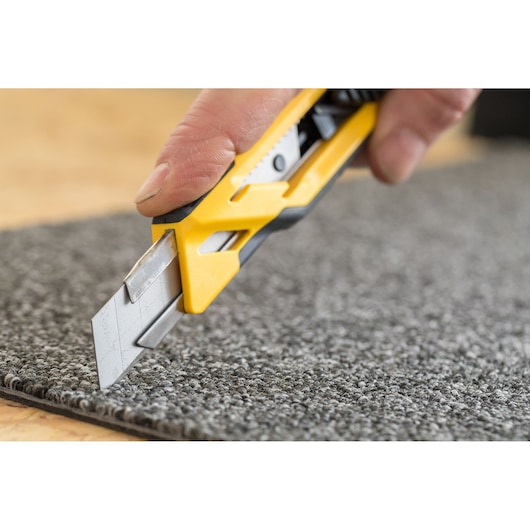 STANLEY STHT10266-0 hobbymes snijdt grijs tapijt, close-up foto, gele en zwarte handgreep zichtbaar.