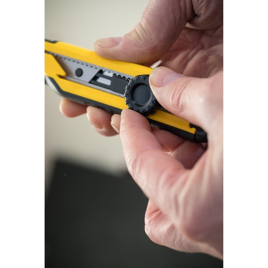 Stanley STHT10268-0 gereedschapsmes close-up met mesafstelwiel vastgehouden in hand.