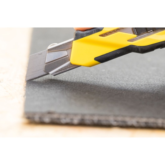 STANLEY STHT10270-0 stanleymes met gele handgreep snijdt zwart materiaal, close-up fotografie.