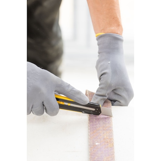 Stanley STHT10345-0 hobbymes snijdt materiaal, foto toont handschoenen die het gereedschap gebruiken.