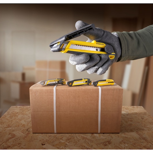 STANLEY STHT10500-0 geel-zwart hobbymes in gebruik om een kartonnen doos te openen, zijaanzicht.