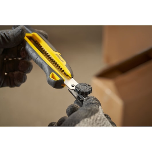 STANLEY STHT10500-0 gereedschapsmes met geel-zwarte handgreep in gebruik, close-up foto.