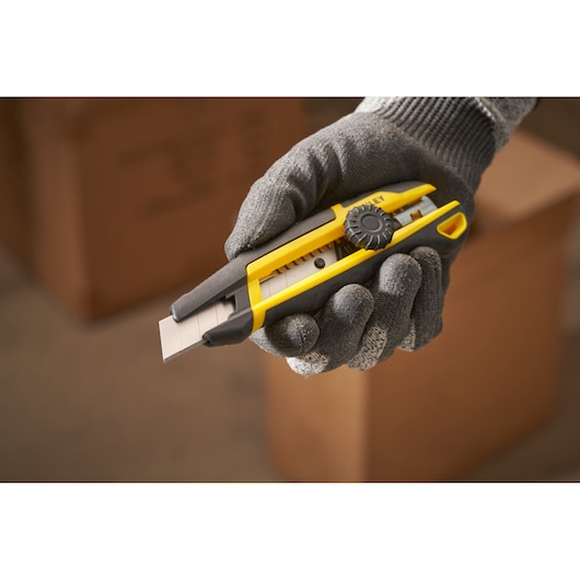 STANLEY STHT10500-0 afbreekmes met geel-zwarte handgreep vastgehouden in handschoen, zijaanzicht.
