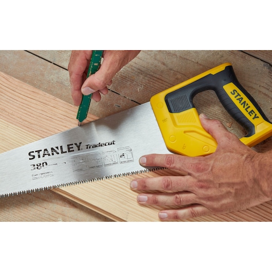 STANLEY STHT20348-1 handzaag met gele handgreep op hout, close-up van zaagtanden en merkdetails.
