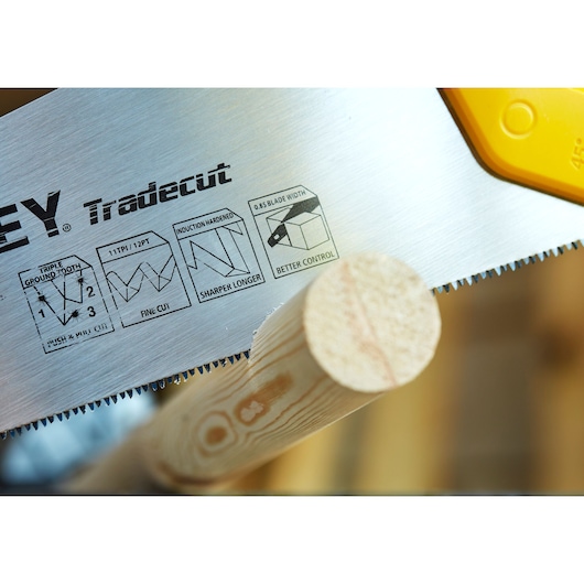STANLEY STHT20349-1 scie à main en gros plan coupant du bois, affichant les détails de la lame Tradecut.