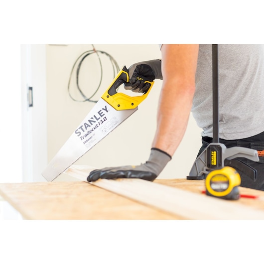 STANLEY STHT20349-1 scie à main avec poignée jaune coupant du bois, gros plan en atelier.