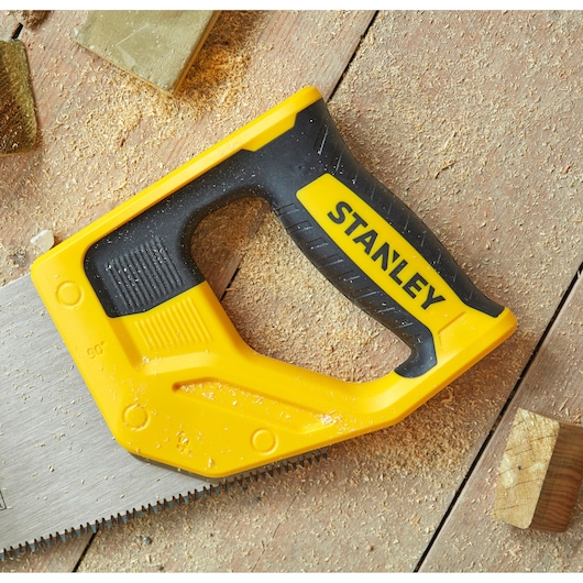 STANLEY STHT20354-1 scie à main avec poignée jaune et noire, vue du dessus, sur surface en bois avec sciure.