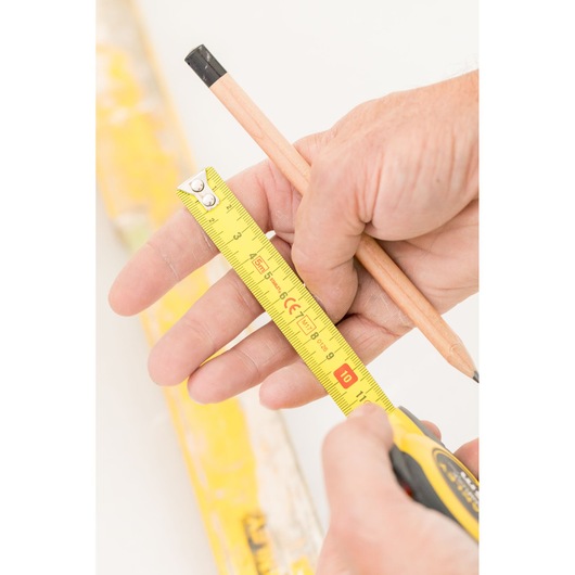 STANLEY STHT36803-0 rolmaat met geel blad en zwart huis, close-up foto in hand met potlood.