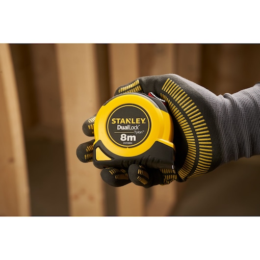 Foto van STANLEY STHT36804-0 rolmaat, geel en zwart, 8 m lang, vastgehouden door een gehandschoende hand, categorie fotografie.