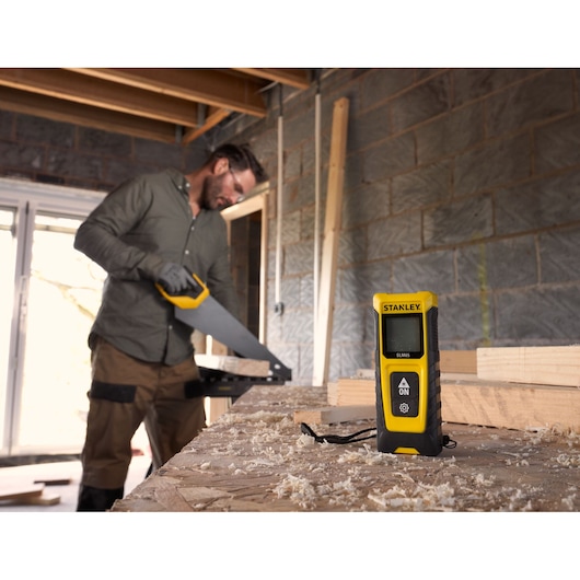 STANLEY STHT77065-0 télémètre laser sur établi dans atelier de menuiserie, design jaune et noir.